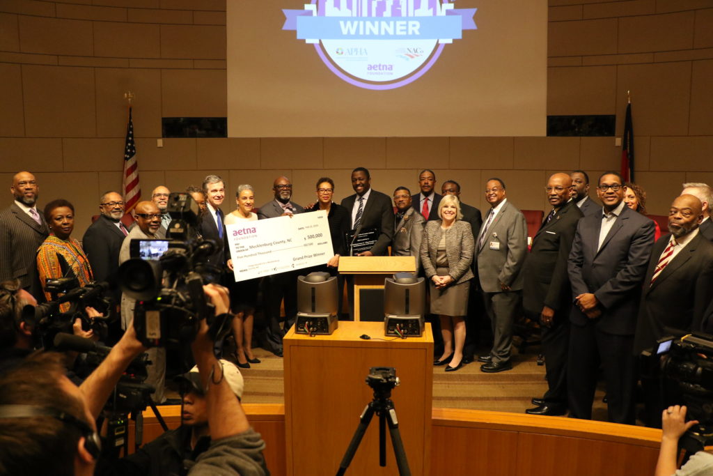 Mecklenburg County's Public Health department, along with Governor Roy Cooper, program participants and community stakeholders, accepts the Healthiest Cities and Counties Challenge grand prize award for the Village HeartBEAT program.