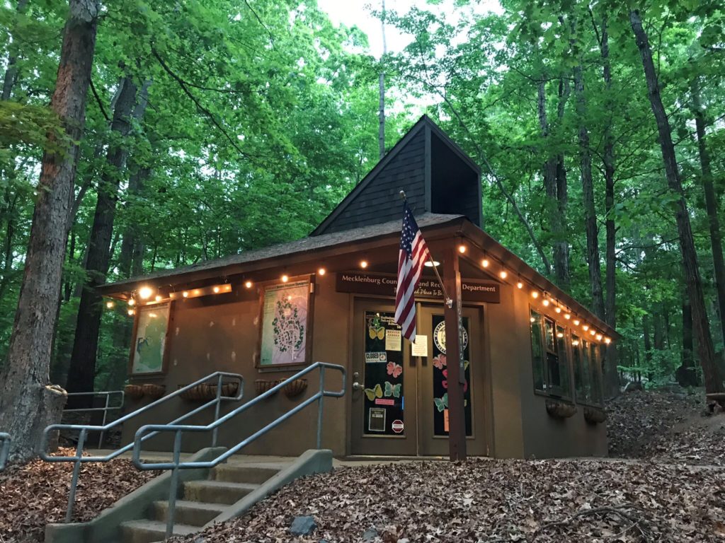 McDowell Nature Center standing among the trees, lit up with string lights and beckoning you to visit during your staycation.
