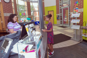 Young girl checking out at the library desk.