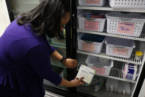 County Nurse Pulls a Vaccination from a Refrigerator
