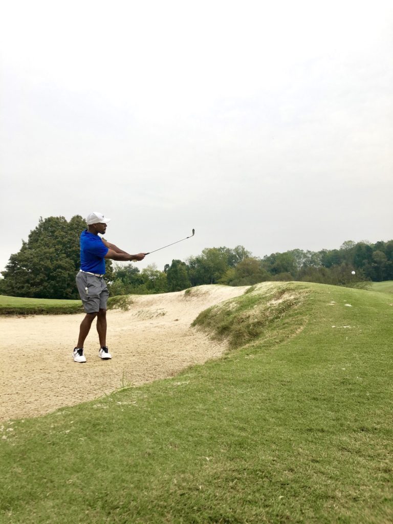 Man golfing from sand trap