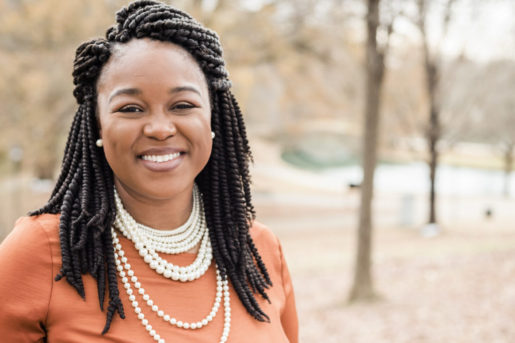 Darcia Sanders standing in front of trees, smiling.