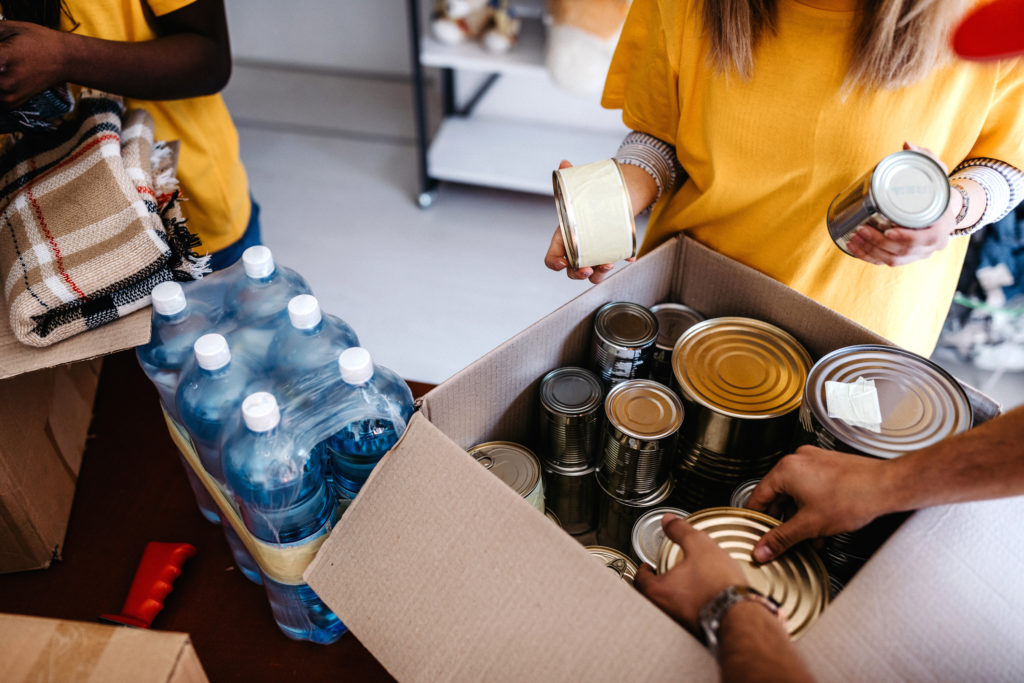 Group of people putting canned goods into boxes to help homeless neighbors