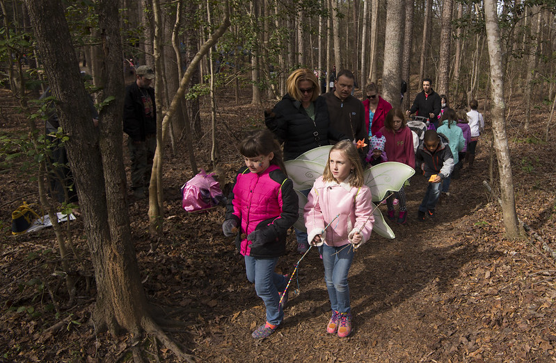 Children marching through the woods, some wearing wings