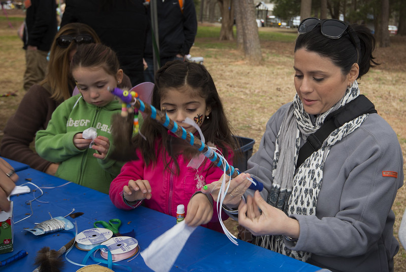 Four people decorating various things, including a wand, at the craft table.