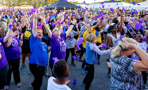 People cheering, throwing purple in the air at a Relay for Life event