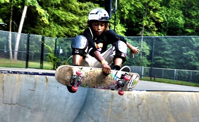 Child wearing protective gear catching air on a skateboard 