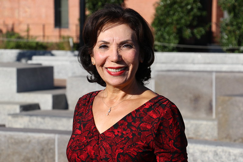A portrait of school health nutritionist Sahsine Davis wearing a red dress smiling brightly at the camera