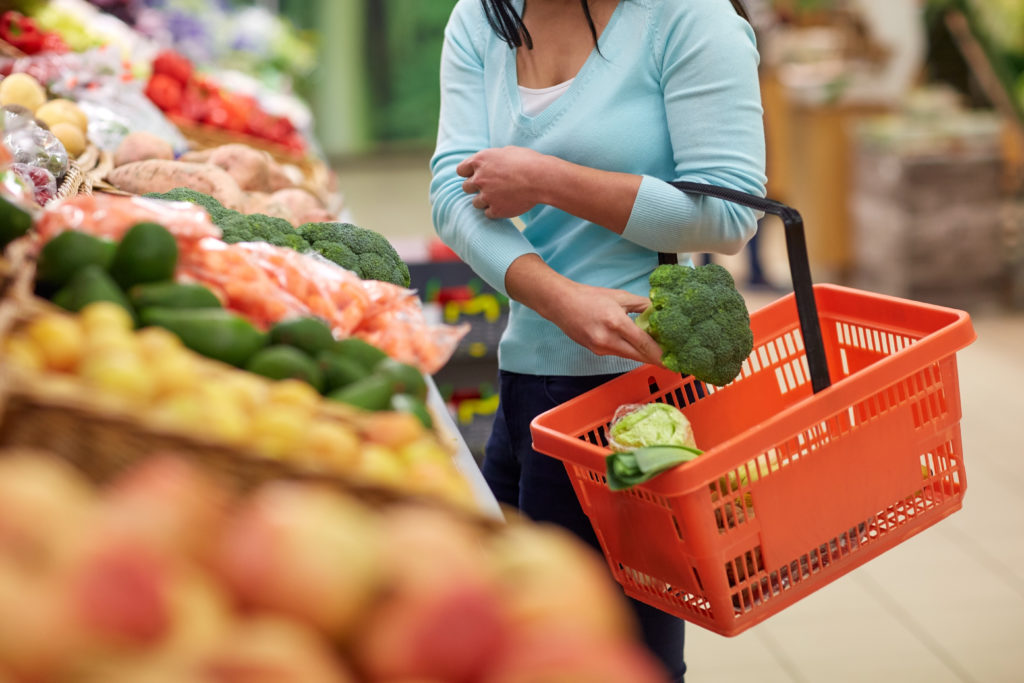 Woman buying vegetables at grocery store.