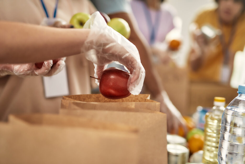 volunteers sorting and stuffing brown paper bags with food