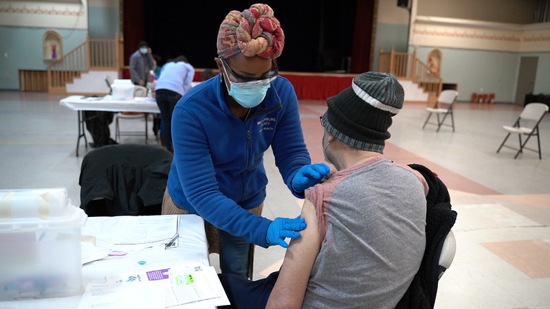 Nurse giving an adult a shot in their arm.