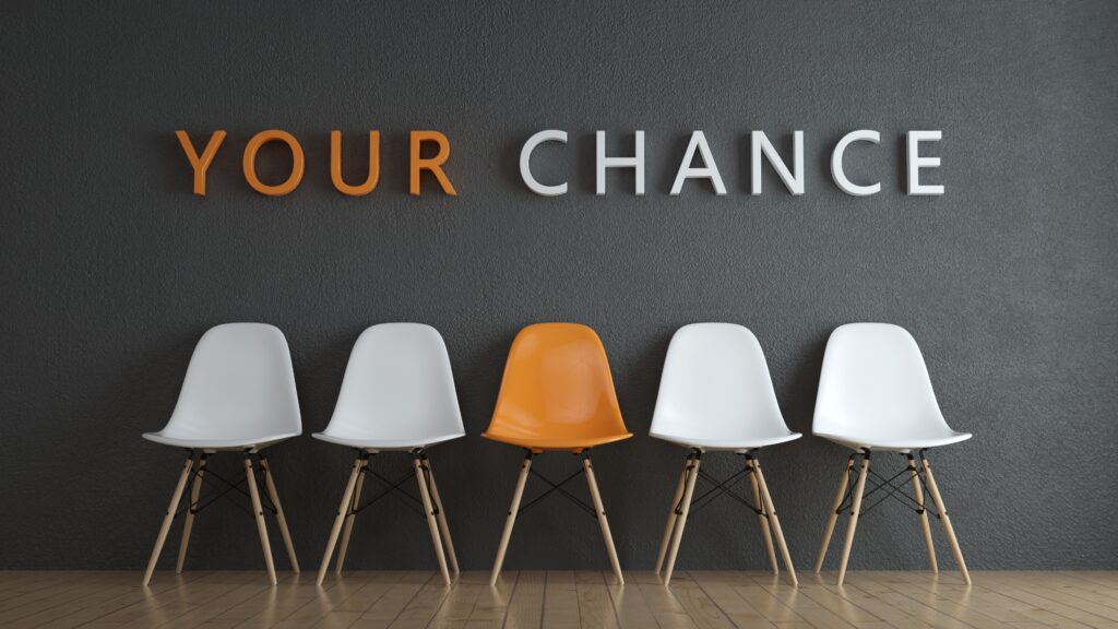 5 chairs in a row. The third chair is color orange and the rest is white. The text Your Chance is above the chairs. Your is in the color orange.
