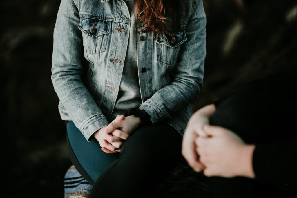 Woman sitting down with her hands crossed on her lap.