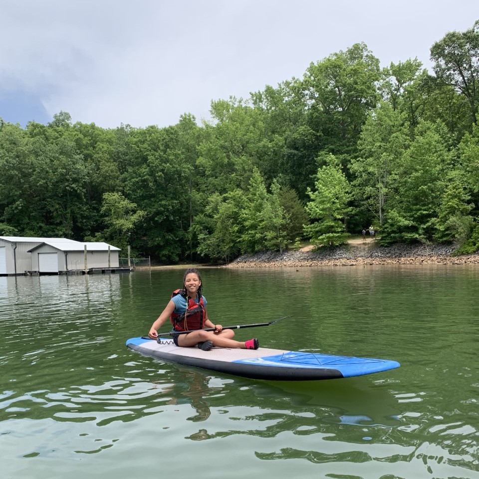 A woman sitting on a paddle board in the water