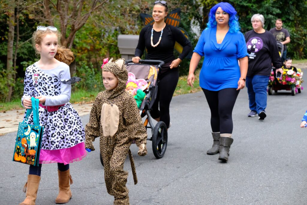 Children and parents dressed up for walking in a neighborhood for Halloween.