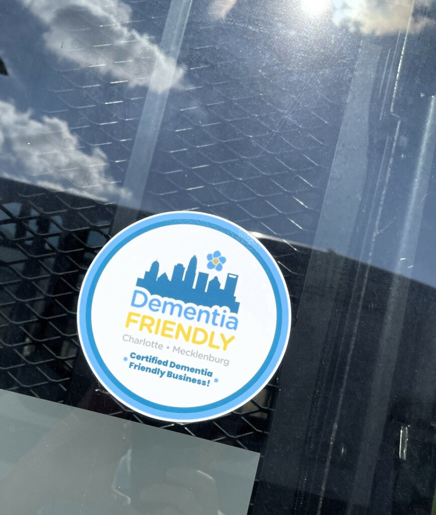 Sticker on a window says "dementia friendly Charlotte Mecklenburg. certified demential friendly business."