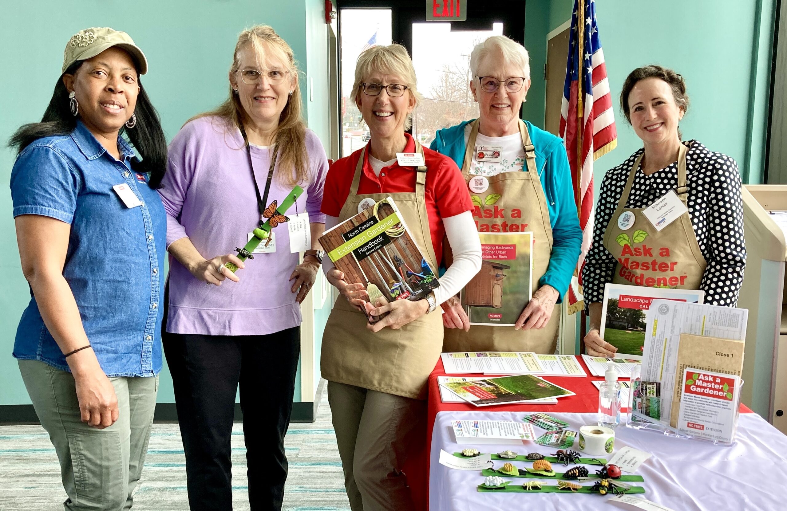 Extension Master Gardener Volunteers stand at a table to educate residents at an event.   