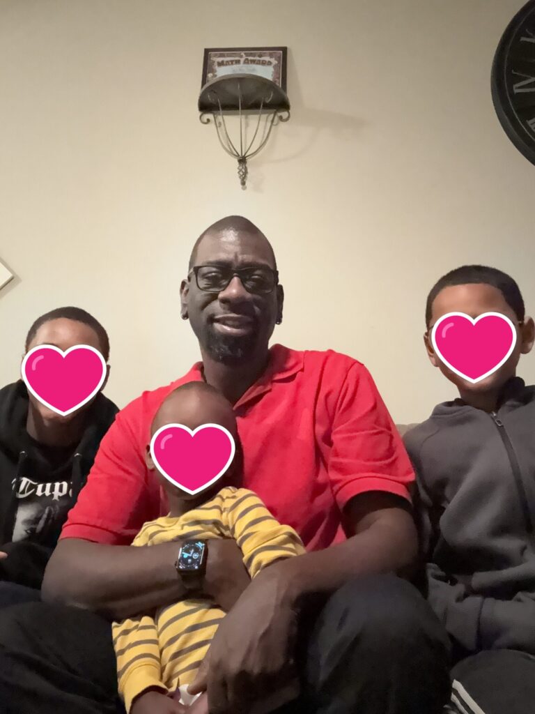 Tim on a couch with three foster sons with pink hearts over their faces